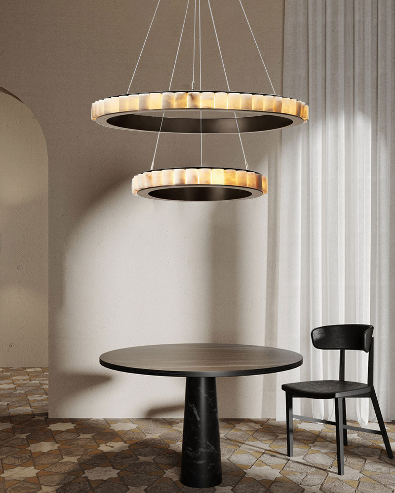 Triple chandelier with alabaster rings above modern black marble table and chair.