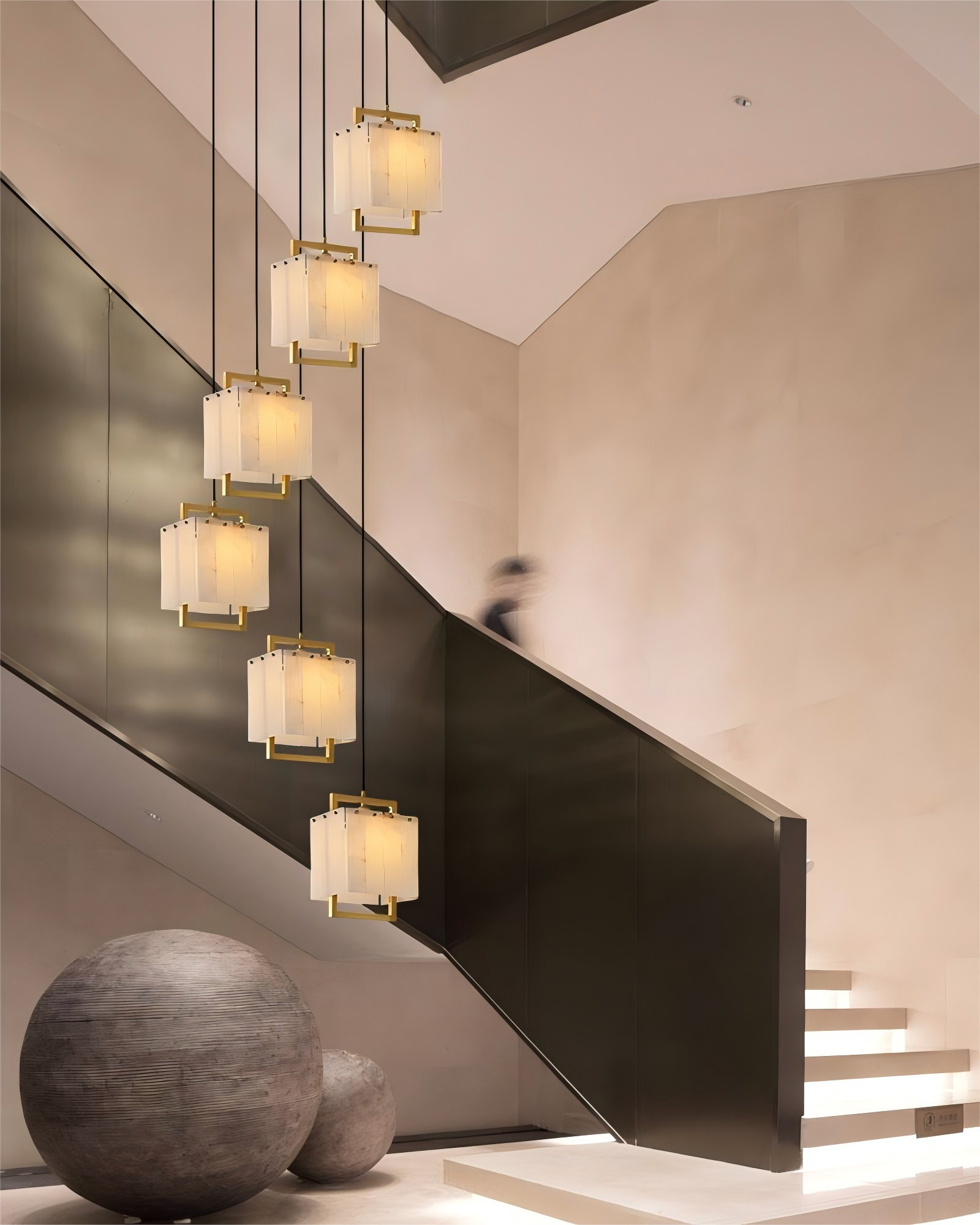 24-light cluster ceiling pendant lamp hanging above modern staircase in bright foyer.