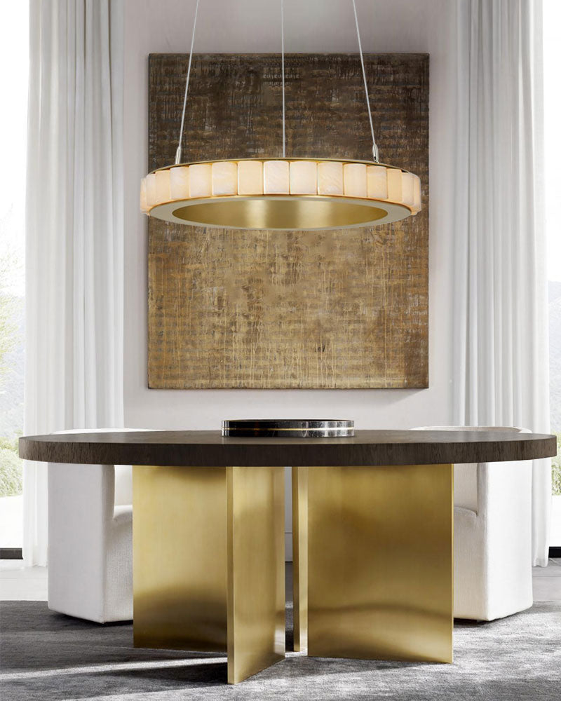 Elegant round chandelier with alabaster rings above sleek gold base dining table.