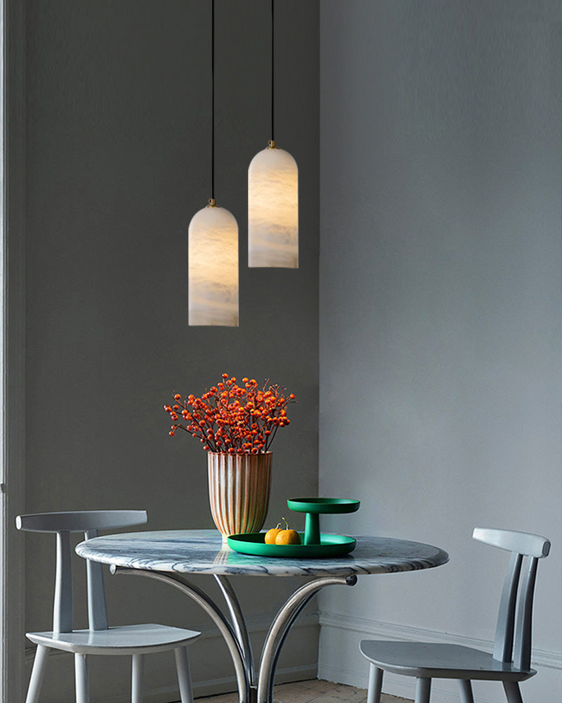 Chic dining area with two marble pendant lamps and a round marble table centerpiece.