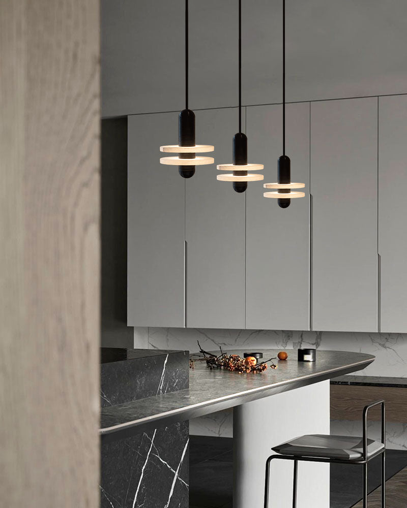 Three modern pendant lights above marble kitchen countertop with minimalist design.