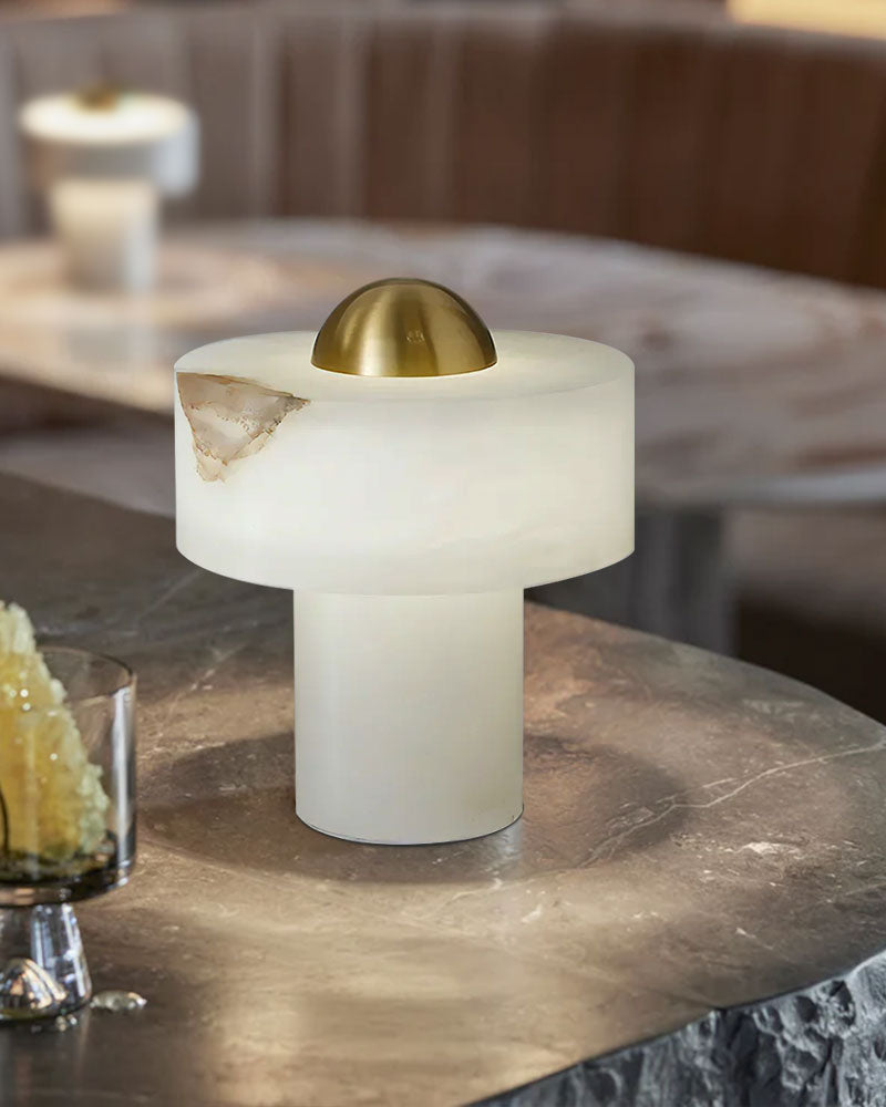 Modern white and brass stone alabaster table lamp on a marble surface