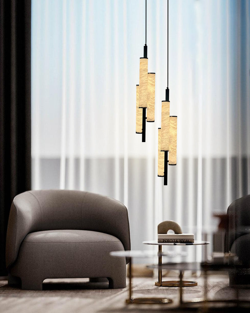 Elegant trio of cylindrical alabaster pendant lights above a modern armchair and coffee table.