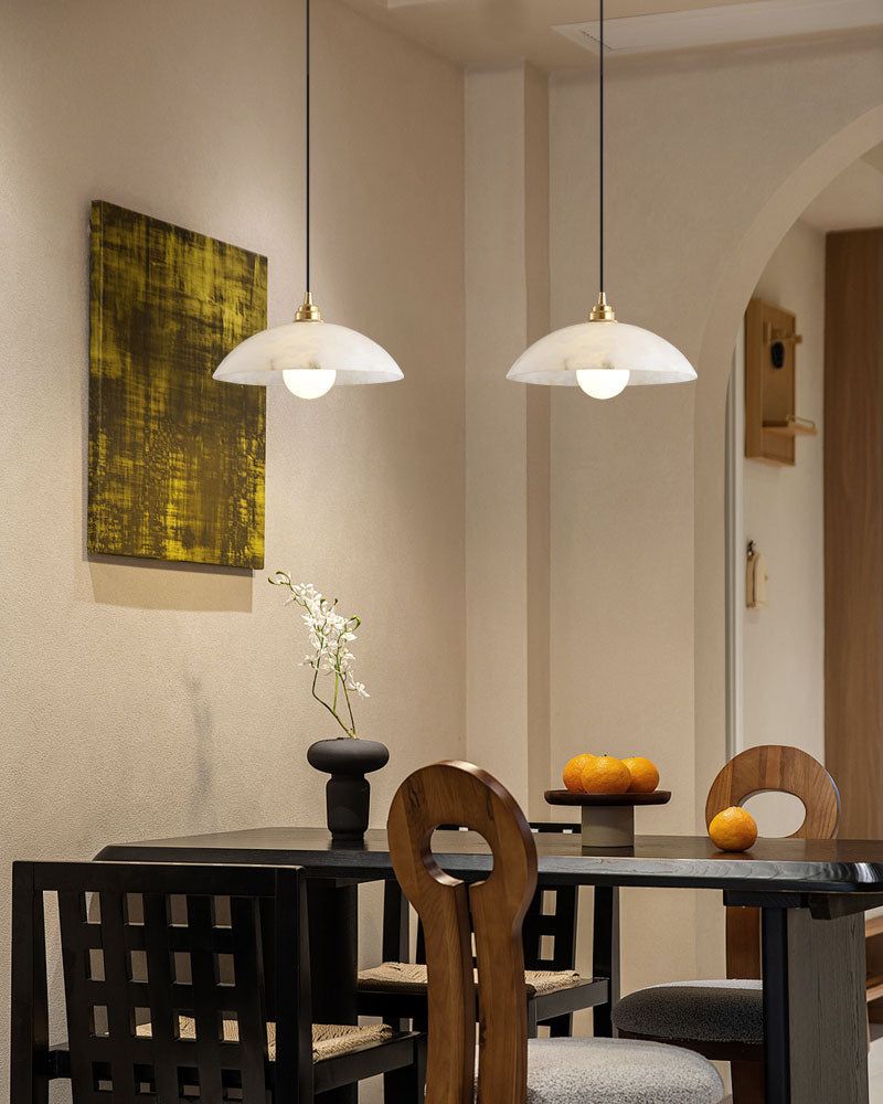 Natural stone pendant lamps above modern table with minimalist decor and yellow artwork.