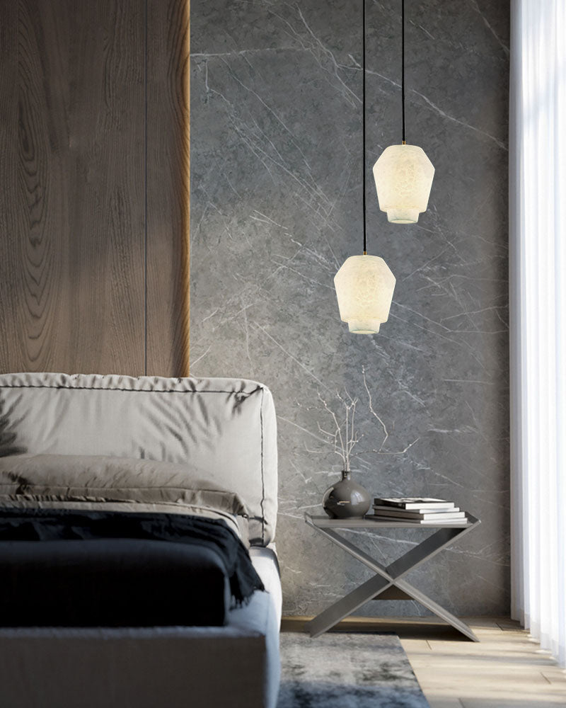 Alabaster pendant lamps illuminating a modern bedroom with sleek bedside table.