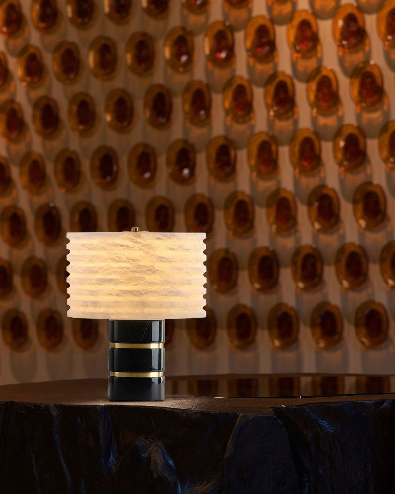 G9 Cloud marble table lamp with textured alabaster shade on a dark surface, amber wall behind.