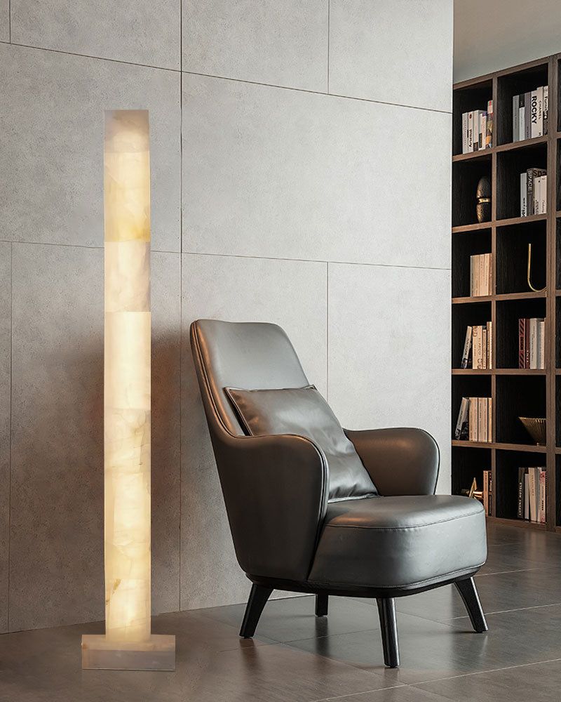 Alabaster column floor lamp beside modern black armchair in stylish living room