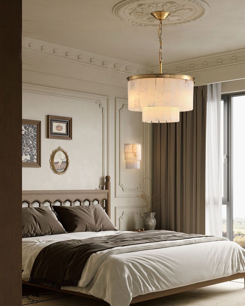 Brass-trimmed alabaster chandelier hanging above a chic modern bedroom with earthy tones