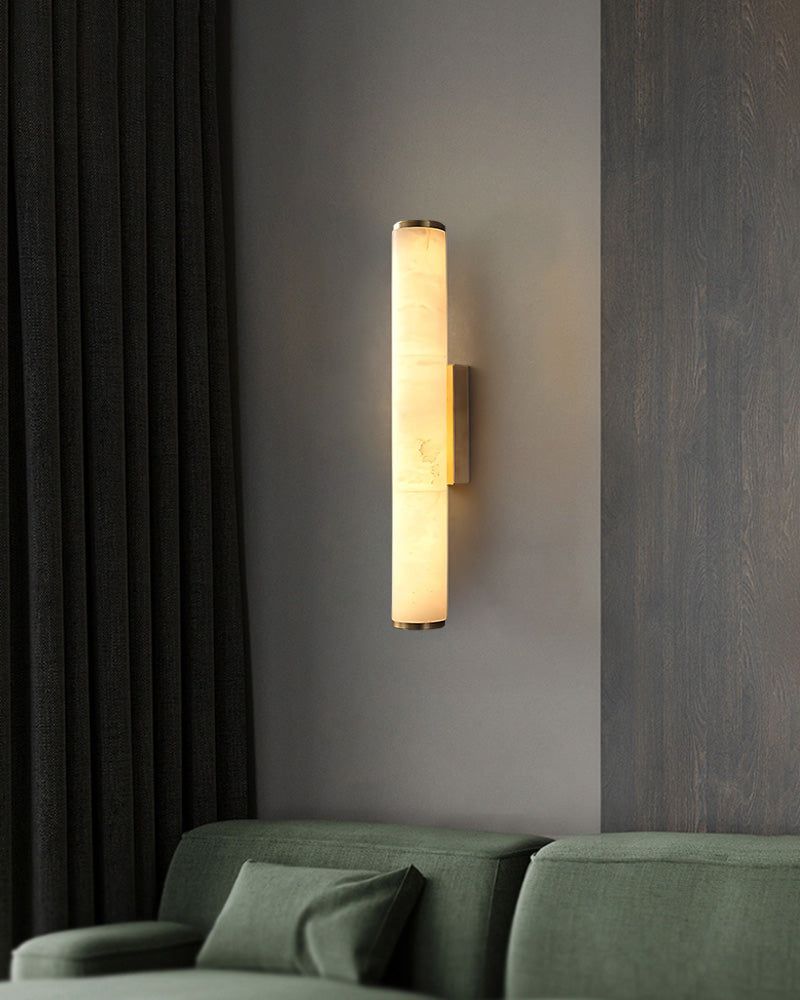 Cylindrical alabaster wall sconce lamp casting warm light in modern living space