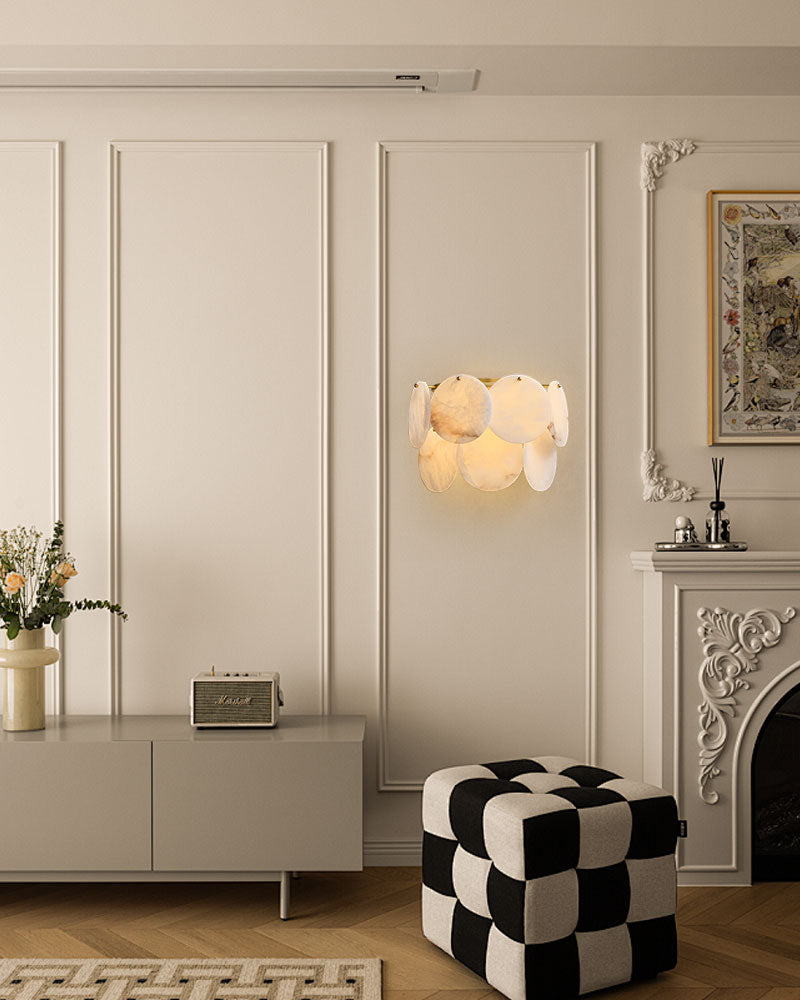 Elegant bedroom with brass Spanish Alabaster Shell sconce glowing above a stylish checkered ottoman