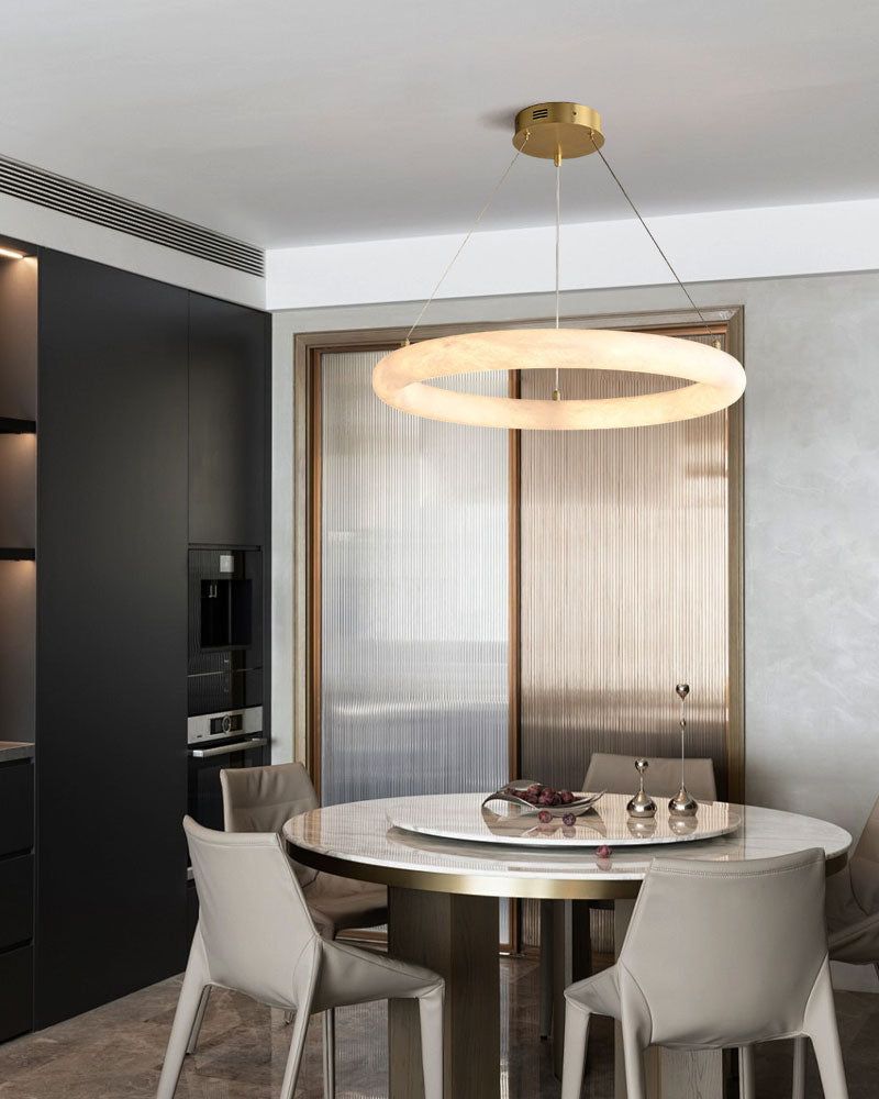 Elegant circular pendant light above modern round dining table with beige chairs