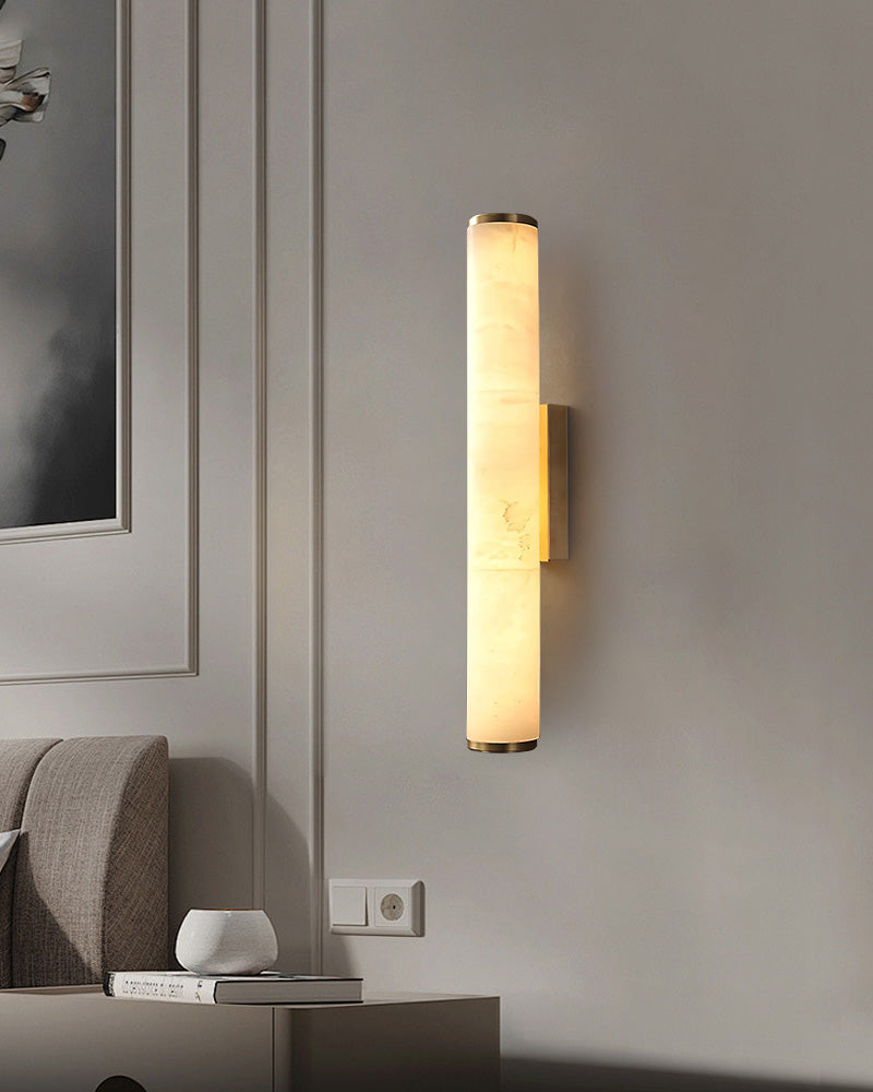 Elegant cylindrical alabaster wall sconce lamp casting warm light in chic living room