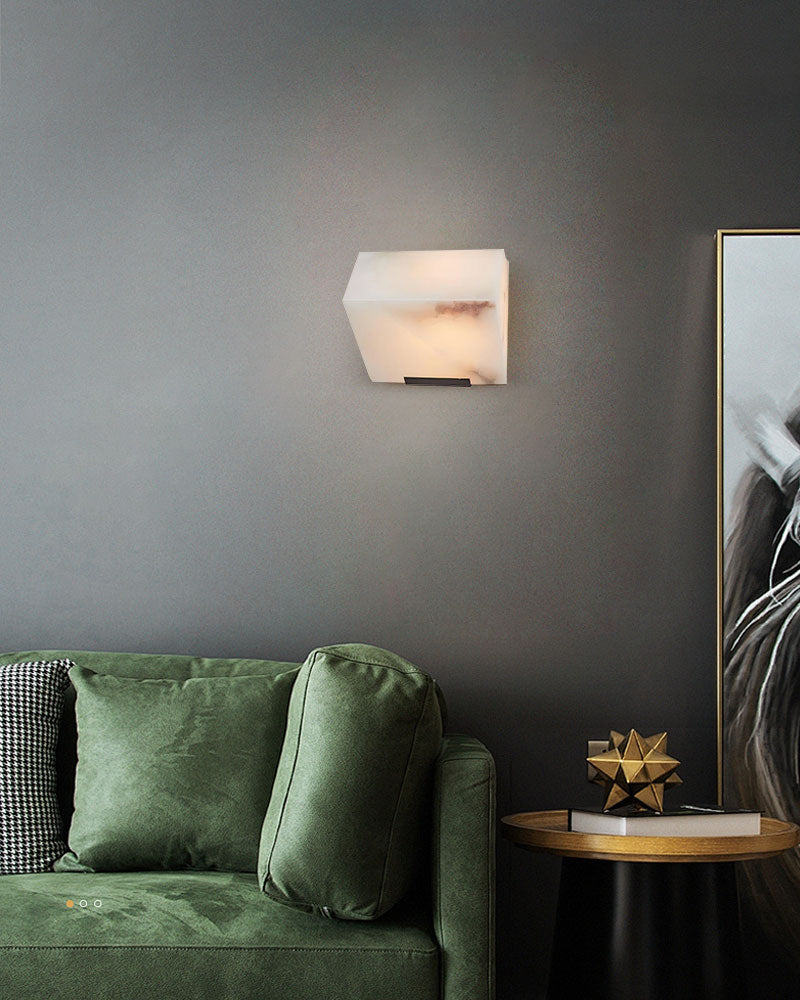 Geometric LED alabaster wall sconce illuminating stylish green sofa and decor