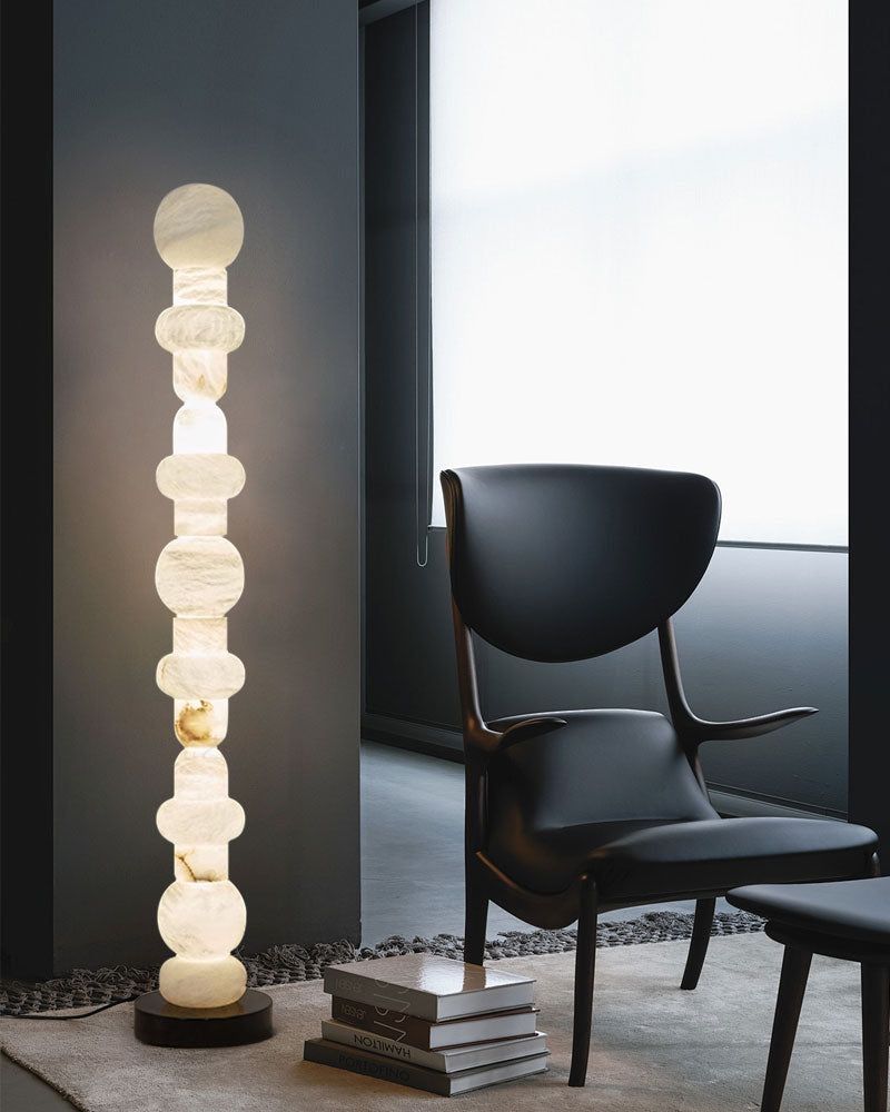Geometric alabaster floor lamp beside a sleek black chair in contemporary interior