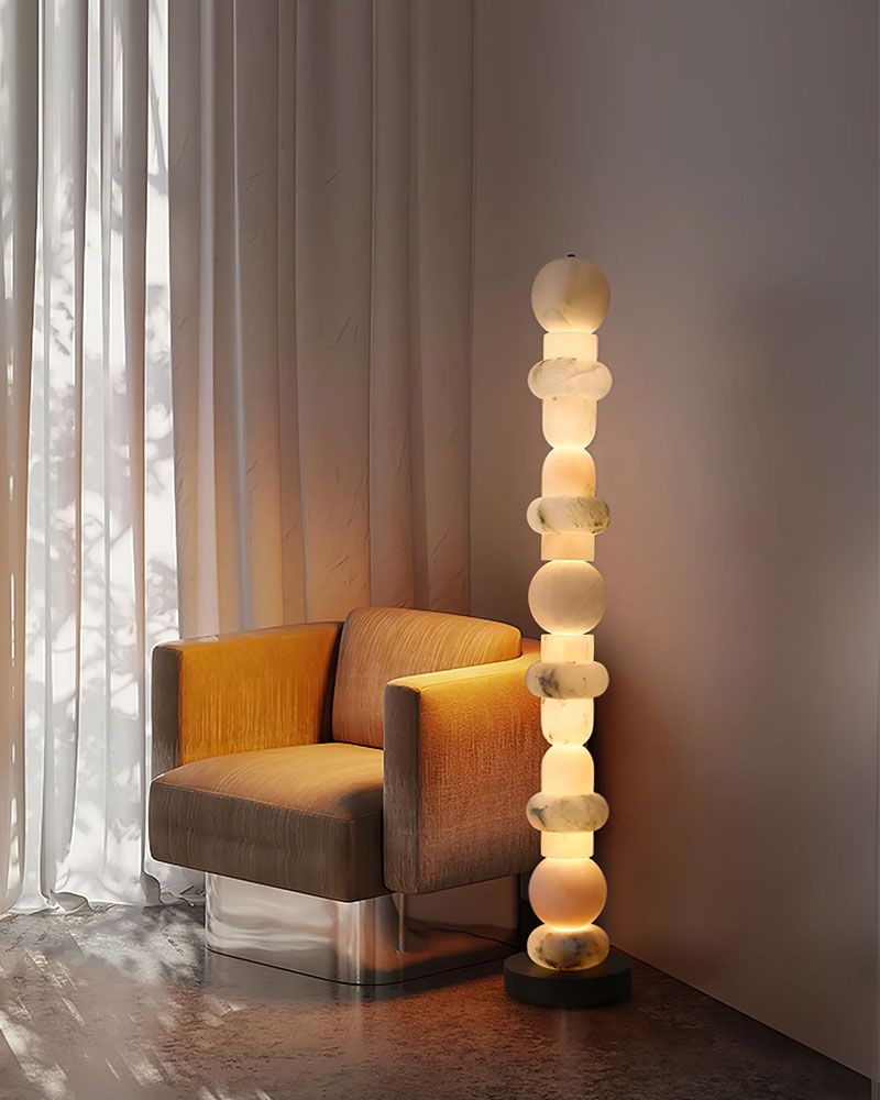 Geometric alabaster floor lamp beside cozy beige armchair in softly lit room