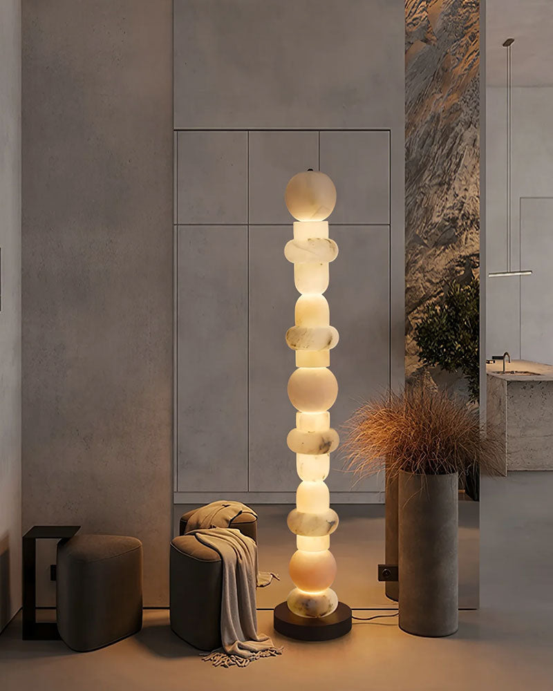 High alabaster floor lamp with geometric design illuminating modern room with gray chair
