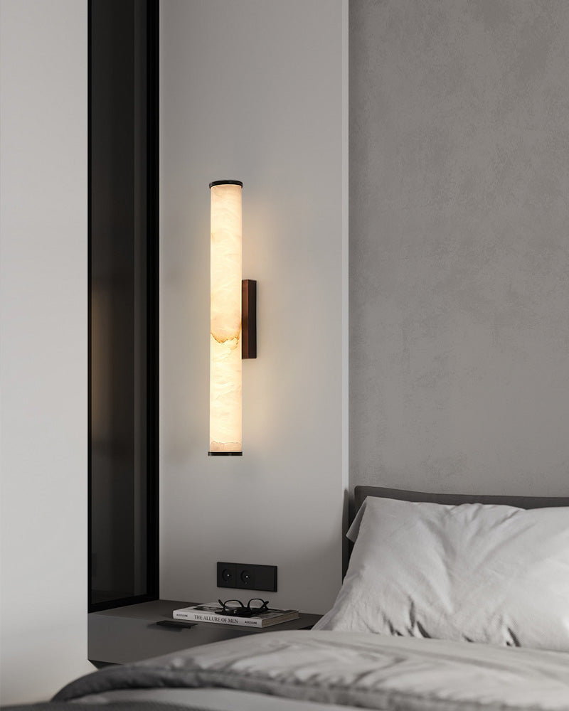 Cylindrical alabaster wall sconce lamp illuminating contemporary bedroom design