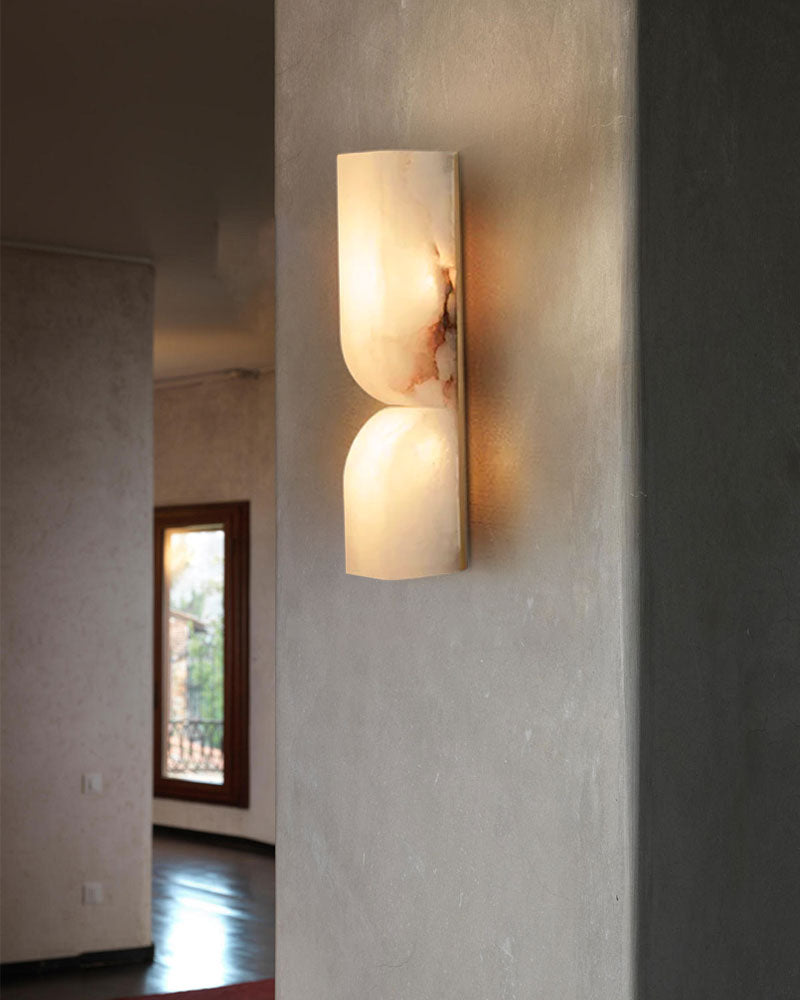 Curved alabaster wall sconce illuminating a stylish gray wall in modern decor.