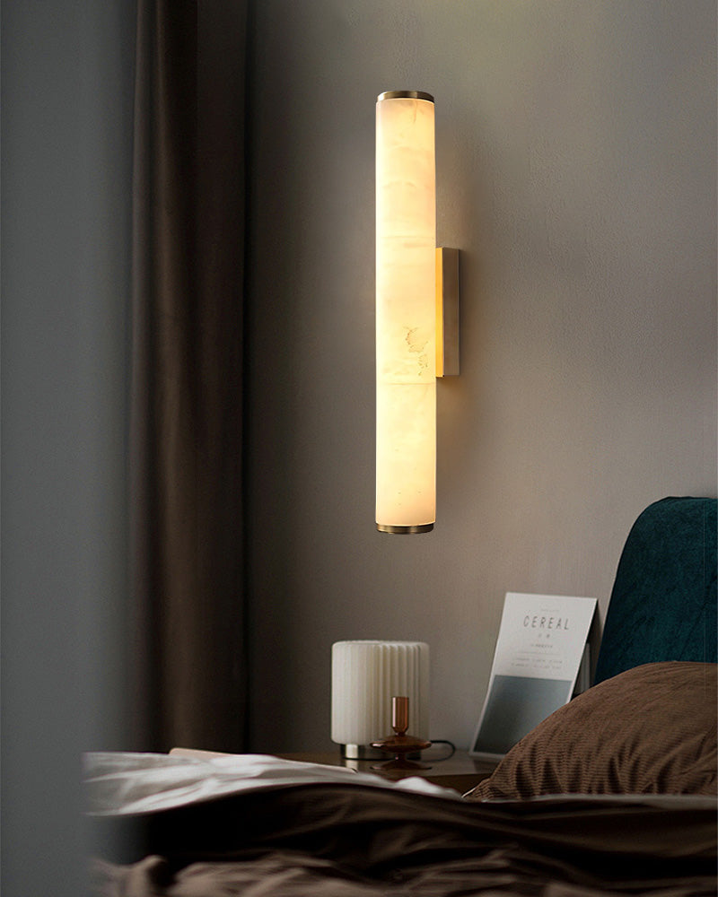 Cylindrical alabaster wall sconce illuminating sophisticated bedroom decor