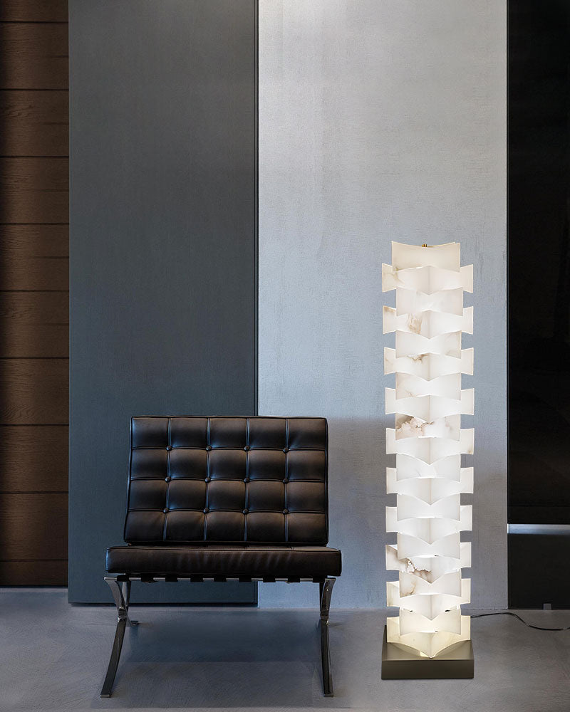 Modern stacked LED floor lamp with alabaster shade next to black lounge chair