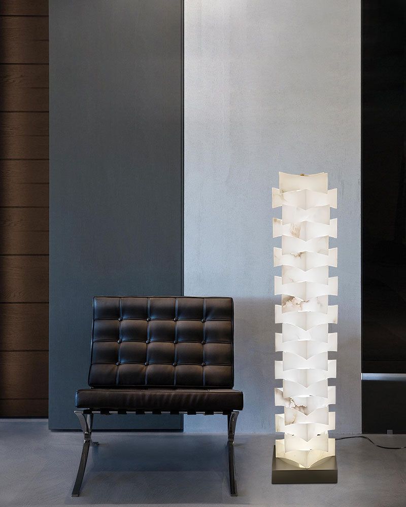 Modern stacked LED floor lamp with alabaster shade next to black lounge chair