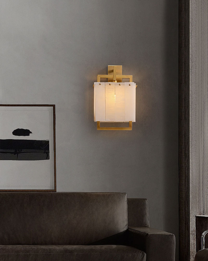 Rubbed brass alabaster wall light fixture beside modern sofa in stylish living room