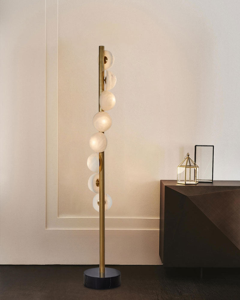 Sleek vertical brass floor lamp with alabaster globes beside dark wood side table