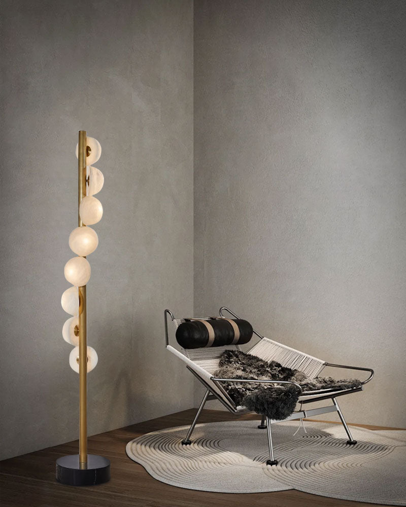 Sleek vertical brass floor lamp with alabaster globes in a cozy modern corner