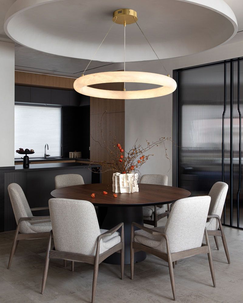 Stylish dining room with round table, upholstered chairs, and sleek circular pendant light
