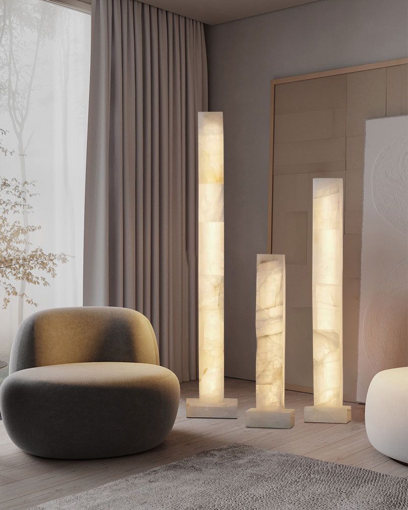 Three tall alabaster column floor lamps illuminating a modern living room with soft light