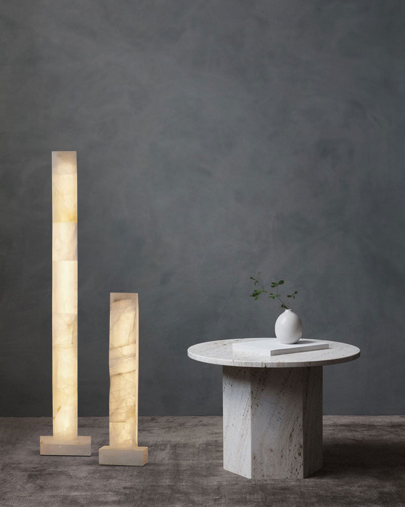 Two tall alabaster lamps in an elegant setting beside a round marble table