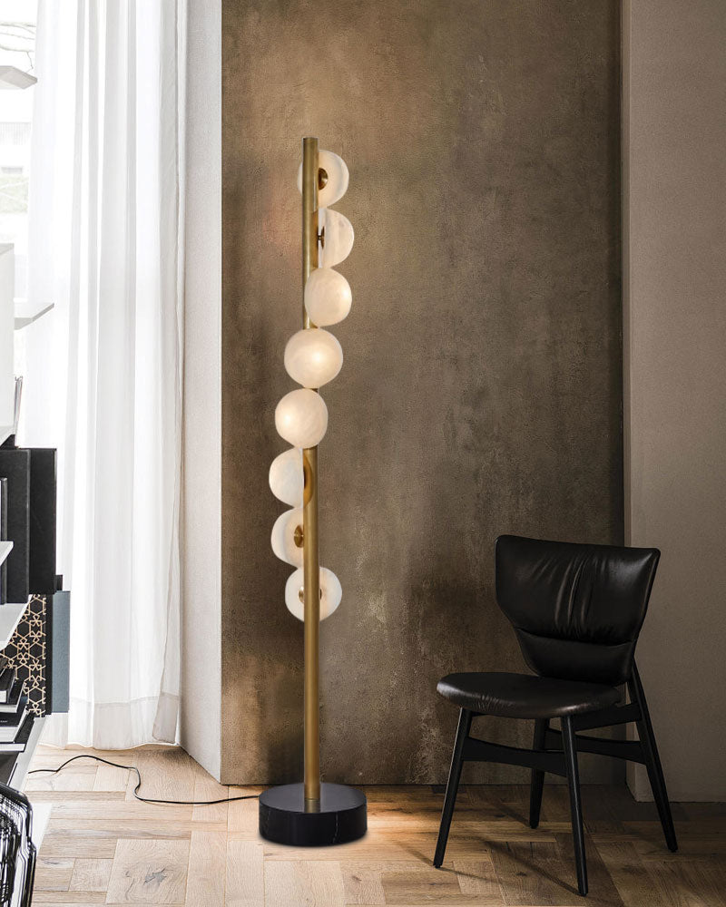 Vertical brass floor lamp with alabaster globes in modern interior setting